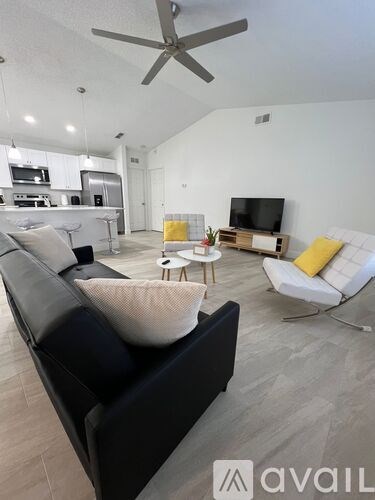 A living room with a black couch and a ceiling fan.