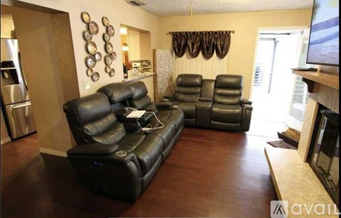 A living room with a black leather couch and a television.