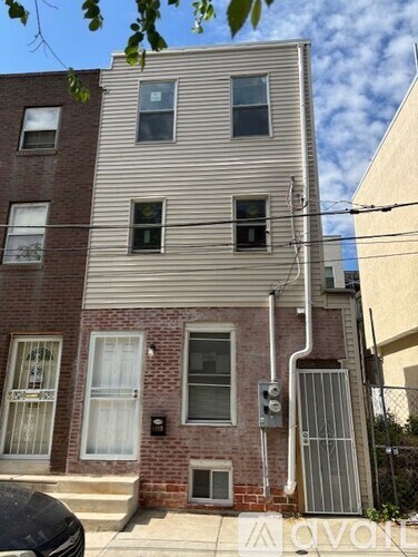 A building with a grey facade and a brick base has a white awning.