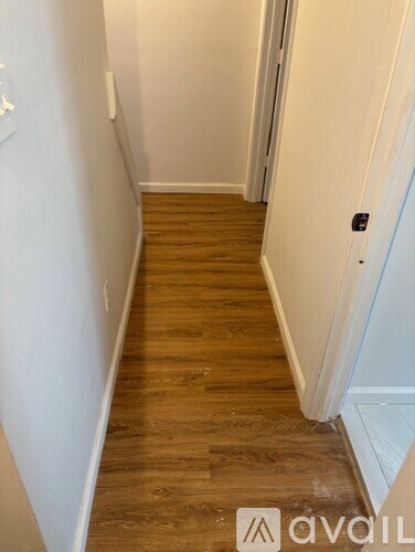 A hallway with wooden floors and white walls.