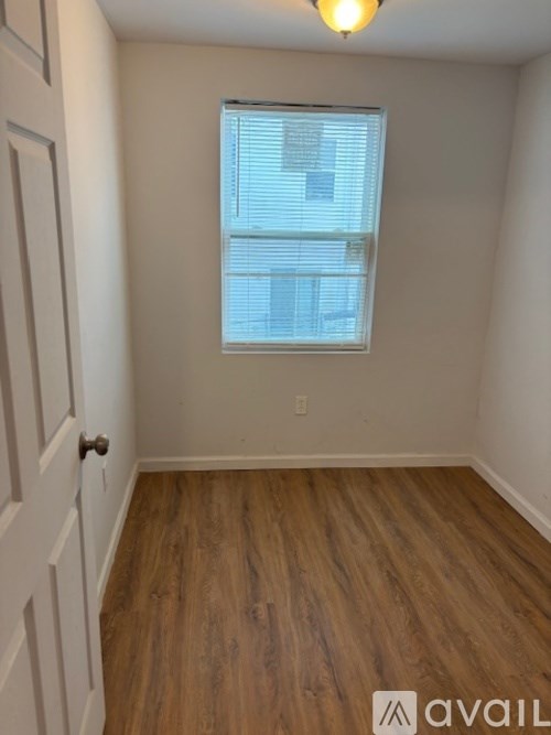 A room with wooden flooring and a window with blinds.