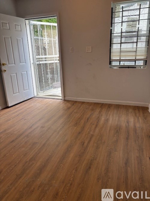 A room with wooden flooring and a white door leading to a balcony.