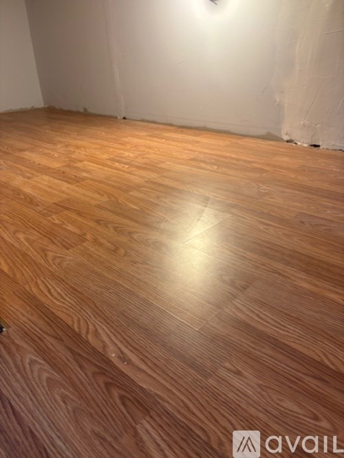 A room with wooden flooring and a white wall.
