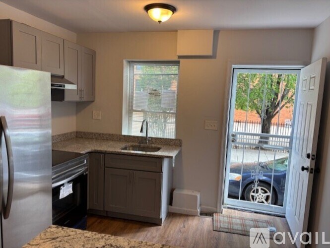 A kitchen with a refrigerator, sink, and cabinets.