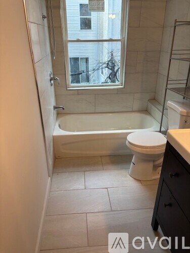 A bathroom with a toilet, tub, and window.