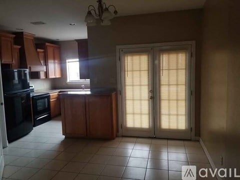A kitchen with wooden cabinets and black appliances is available for rent.