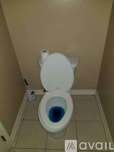 A toilet with blue water in the bowl.