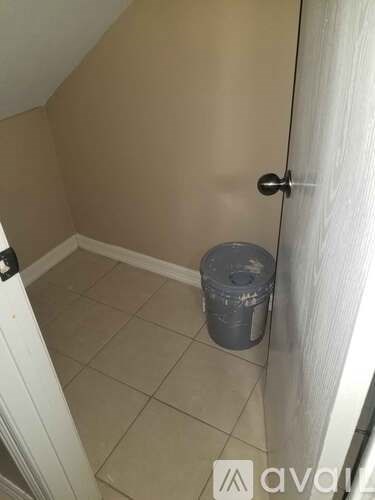 A small room with a trash can and a closed door.