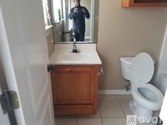 A man is taking a picture of a white toilet in a bathroom.