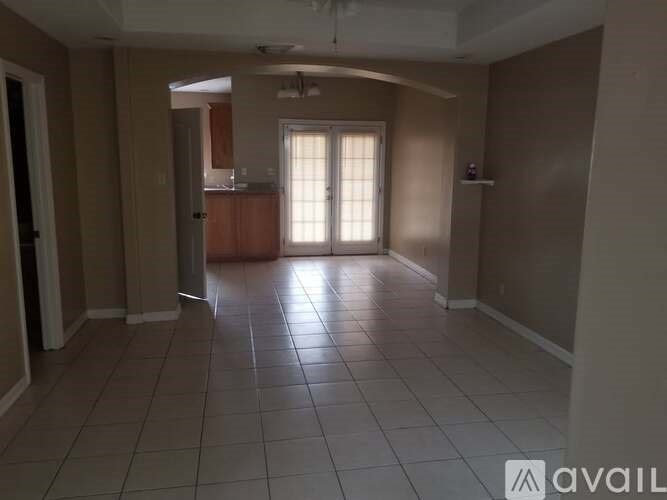 A spacious room with tiled flooring and a sliding glass door.