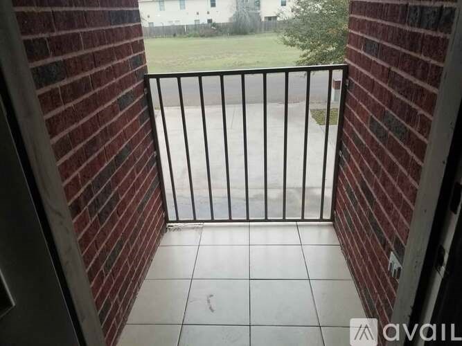 A balcony with a black railing and a view of a grassy area.