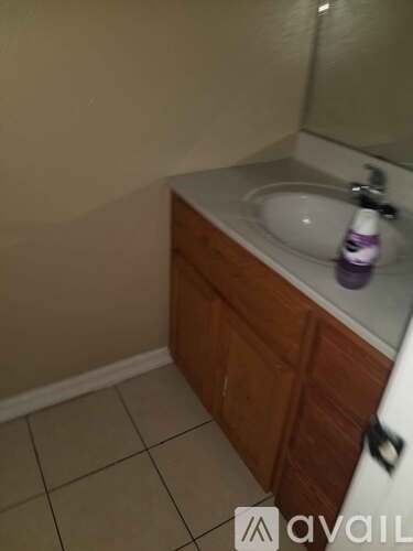 A white sink in a wooden cabinet with a purple bottle on top.