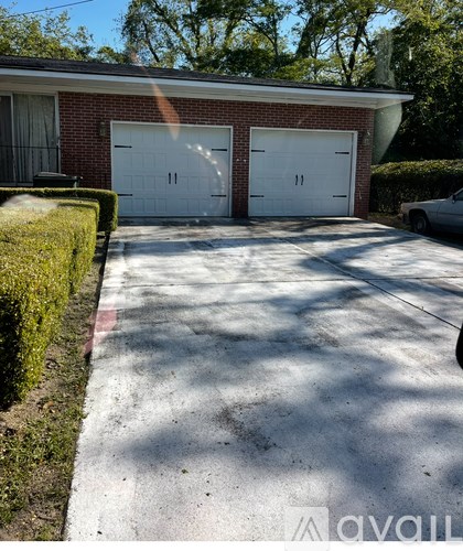 A house with a red brick exterior and two white garage doors.