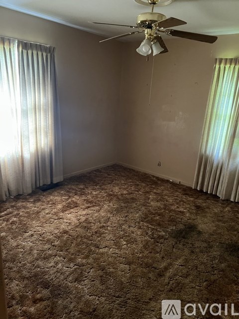 A bedroom with a bed, dresser, and window with curtains.