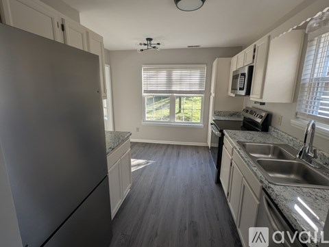 A kitchen with a refrigerator, microwave, and sink.
