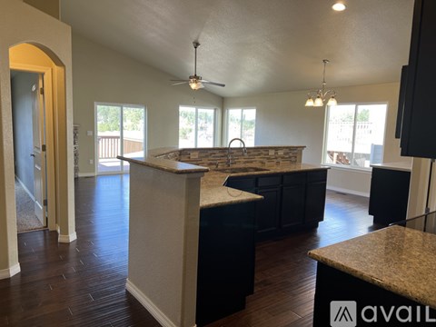 A kitchen with a stone counter top and a ceiling fan.
