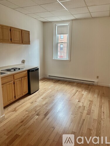 A room with wooden flooring and a window showing a building outside.
