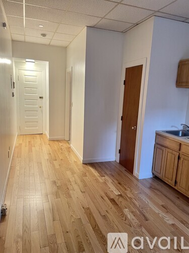 A hallway with wooden floors and white walls.