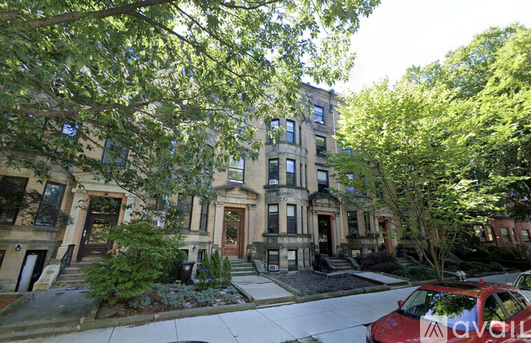 A row of brown and green buildings with a red car in front.