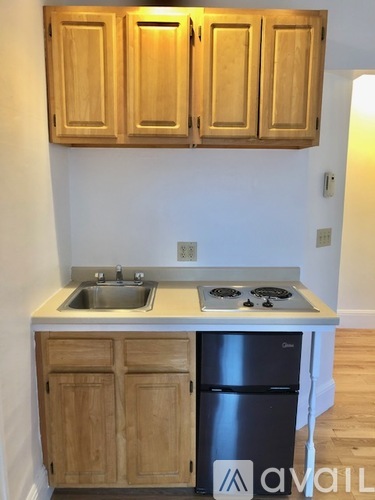 A kitchen with wooden cabinets and a black fridge.