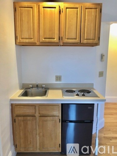 A kitchen with wooden cabinets and a black fridge.