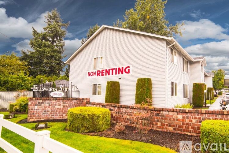 A white house with a sign that says "Now Renting" in front of it.