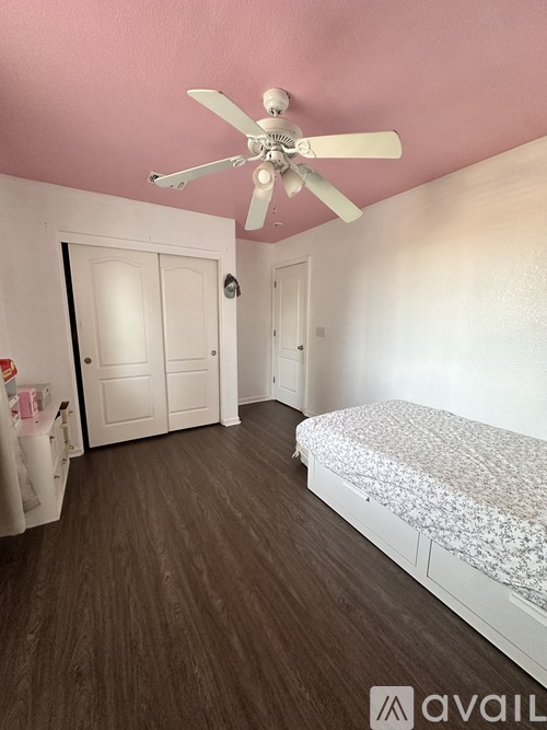 A bedroom with a bed, a ceiling fan, and two doors.