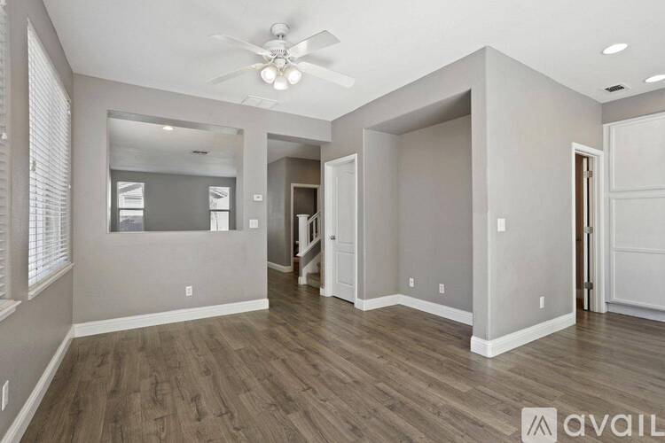 A spacious room with wood flooring and a ceiling fan.