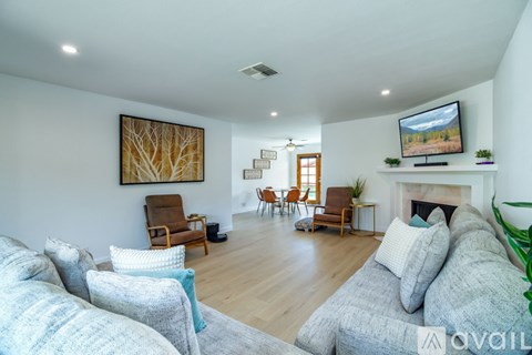A living room with a grey couch and a painting on the wall.