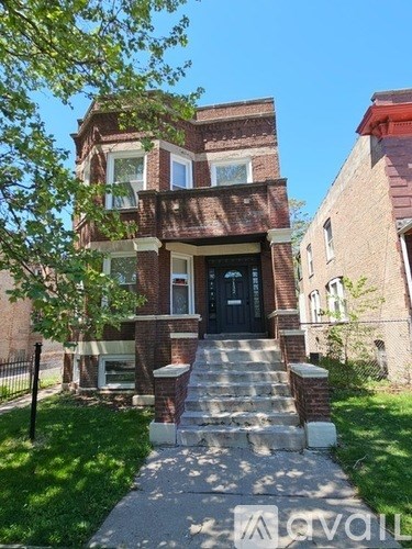 A brick house with a black door and steps leading up to it.