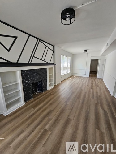 A room with wooden floors and a fireplace with a black mantle.