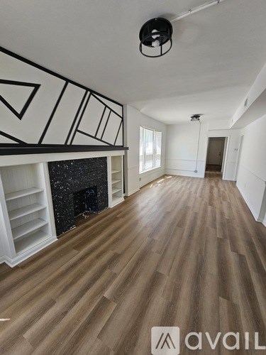 A room with wooden floors and a fireplace with a black mantle.