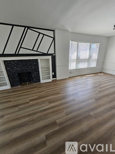 A room with wooden floors and a fireplace with a black surround.