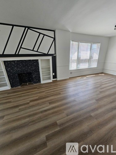 A room with wooden floors and a fireplace with a black surround.