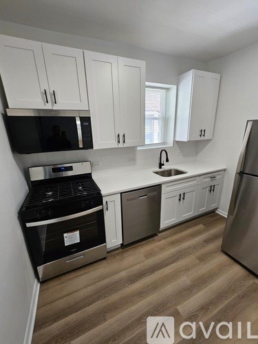 A kitchen with white cabinets and a stainless steel refrigerator.
