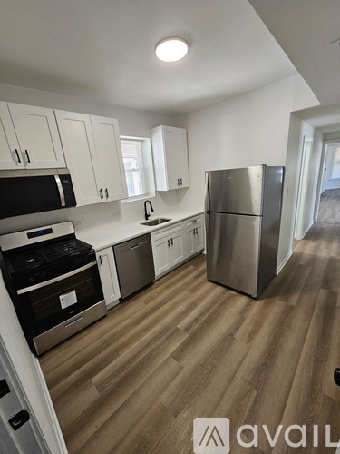A kitchen with white cabinets and a wooden floor.