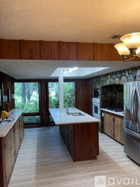 A kitchen with wooden cabinets and a large island in the middle.