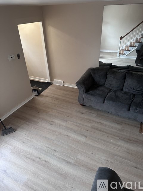 A living room with a grey couch and wooden flooring.