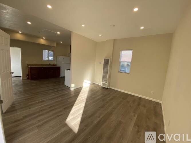 A spacious room with wooden flooring and a large window.