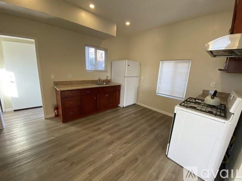 A kitchen with a white stove top oven and wooden flooring.