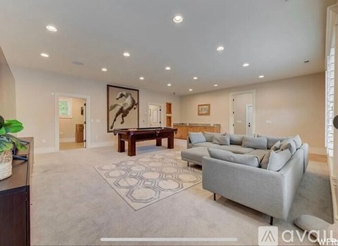 A spacious living room with a grey sofa, a wooden coffee table, and a large abstract painting on the wall.