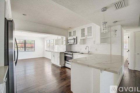 A kitchen with white cabinets and a white island.