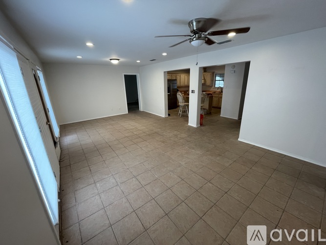 A spacious room with a ceiling fan and tiled flooring.