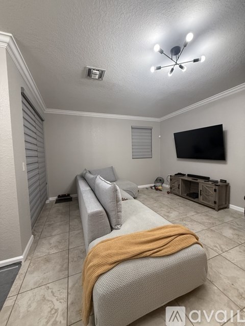 A living room with a grey couch and a television on the wall.