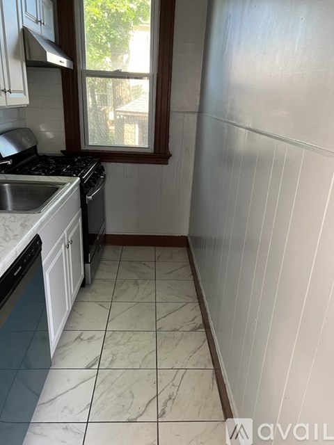 A kitchen with white cabinets and a marble floor.
