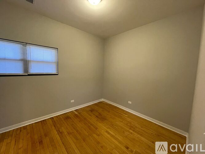 A room with wooden flooring and a window with blinds.