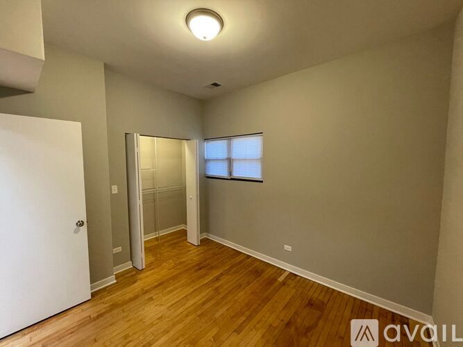 A room with wooden floors and a window with blinds.