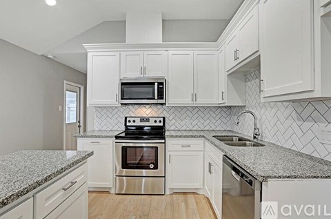 A kitchen with white cabinets and a granite countertop.