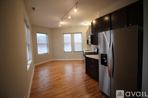 A kitchen with a stainless steel refrigerator and wooden floors.