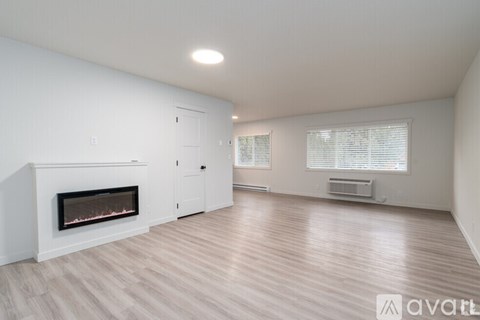 A spacious room with a fireplace and wooden flooring.
